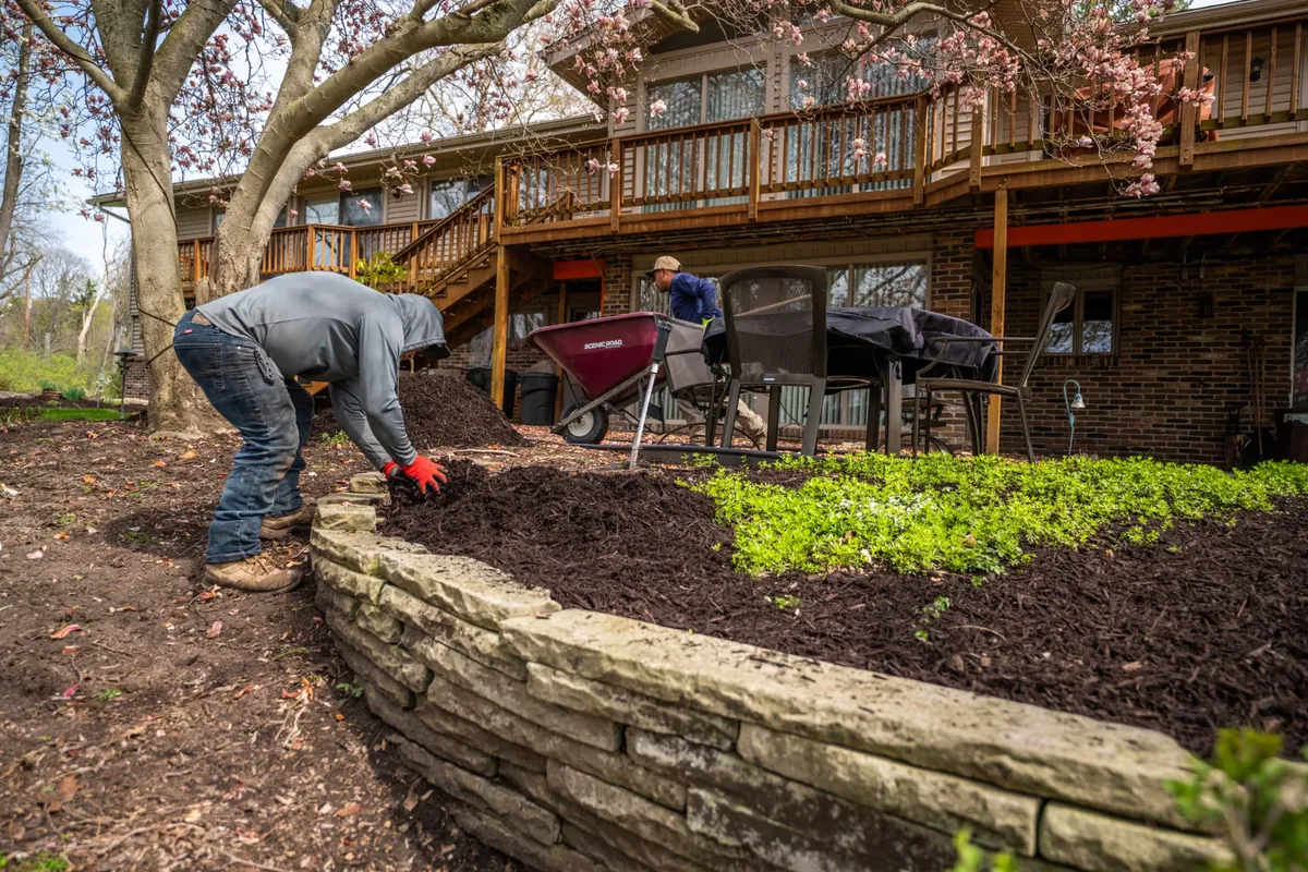 Crew mulching along a stacked stone retaining wall