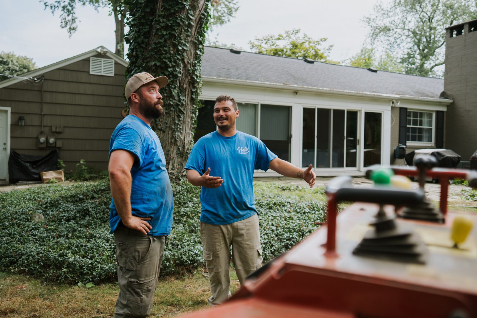 Two crew members discussing a tree job in a backyard