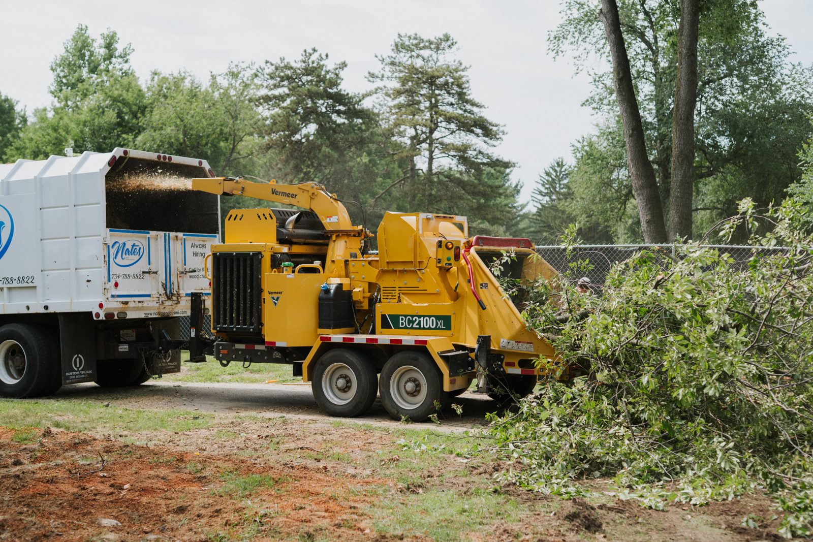 Nate's truck and wood chipper chipping branches at a job site